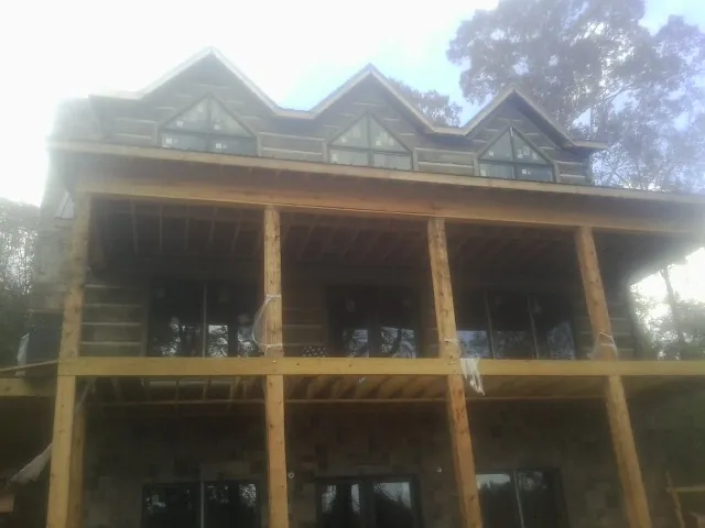 Dormers and porch framing on a large log home under construction — Roof Coating work by our crew in Ortonville