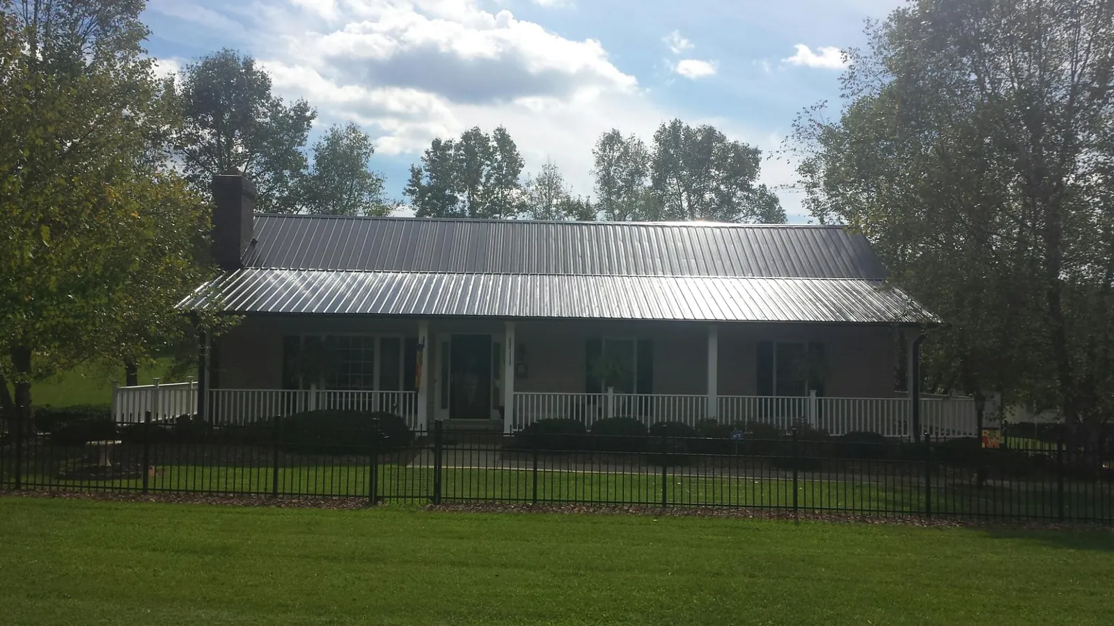 Gray metal roof on a brick ranch with a full width front porch — Gutter Guard Installation work by our crew in Ortonville